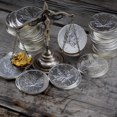 Canada Maple Leaf silver coins compared with gold nuggets on scale