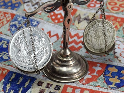 stock image: silver bullion coin and British coin on vintage scale
