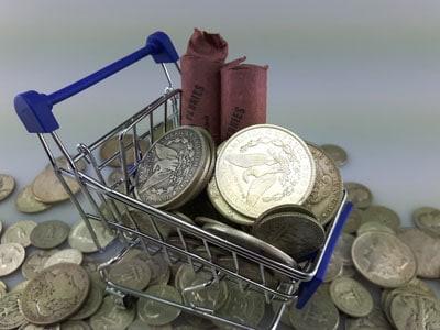 stock image: shopping cart filled with Morgan dollars, quarter dollars, coin rolls
