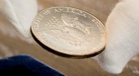 reDollar expert touches silver eagle coin with cotton gloves