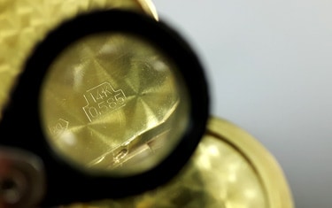 using a magnifying glass for finding the gold marking on jewelry