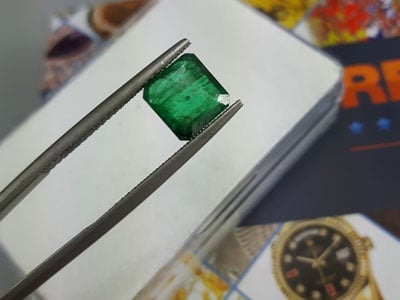 stock image: natural green emerald in tweezer close-up, beryl variety