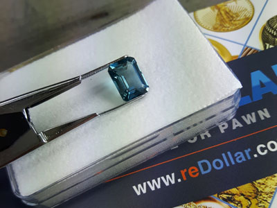 stock image: opened gem display box and blue, loose gemstone