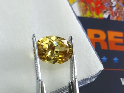 stock image: yellow gemstone in tweezer