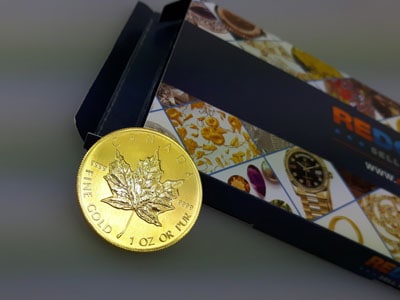 stock image: 1 ounce Maple Leaf gold coin with shipping box