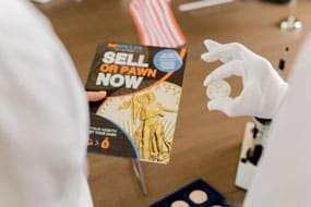 Coin appraiser holding a silver coin over reDollar flyer