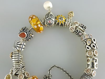 stock image: orange and yellow Pandora bracelet gold, silver, pearl, coral