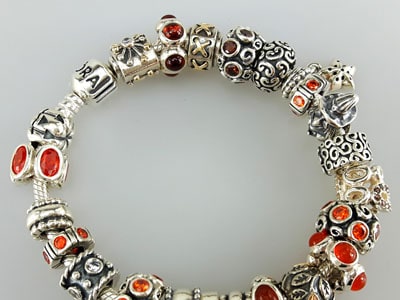 stock image: fully loaded red and orange Pandora bracelet