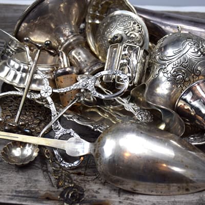 Decorative scrap silver: spoons, mugs, candlestick, bowl, sugar tongs, and cake lifter
