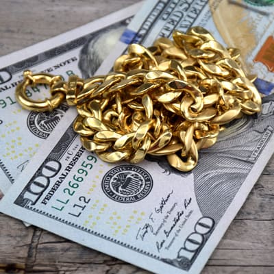 yellow gold chain on 100 USD bill cash