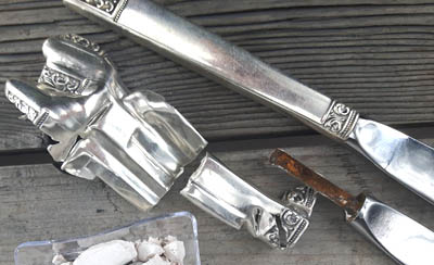parts of a disassembled silver knife: blade, fillings and silver handle