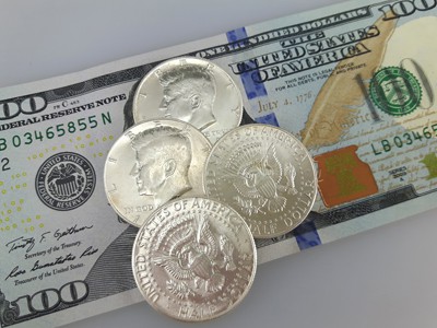 Silver Kennedy Half Dollar coins on banknotes
