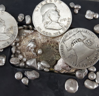 3 Franklin silver half dollars sitting on silver melting equipment